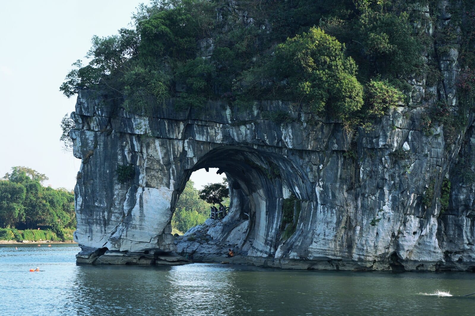 Elephant Trunk Hill's rock arch beside the Li River, with greenery on the cliff top