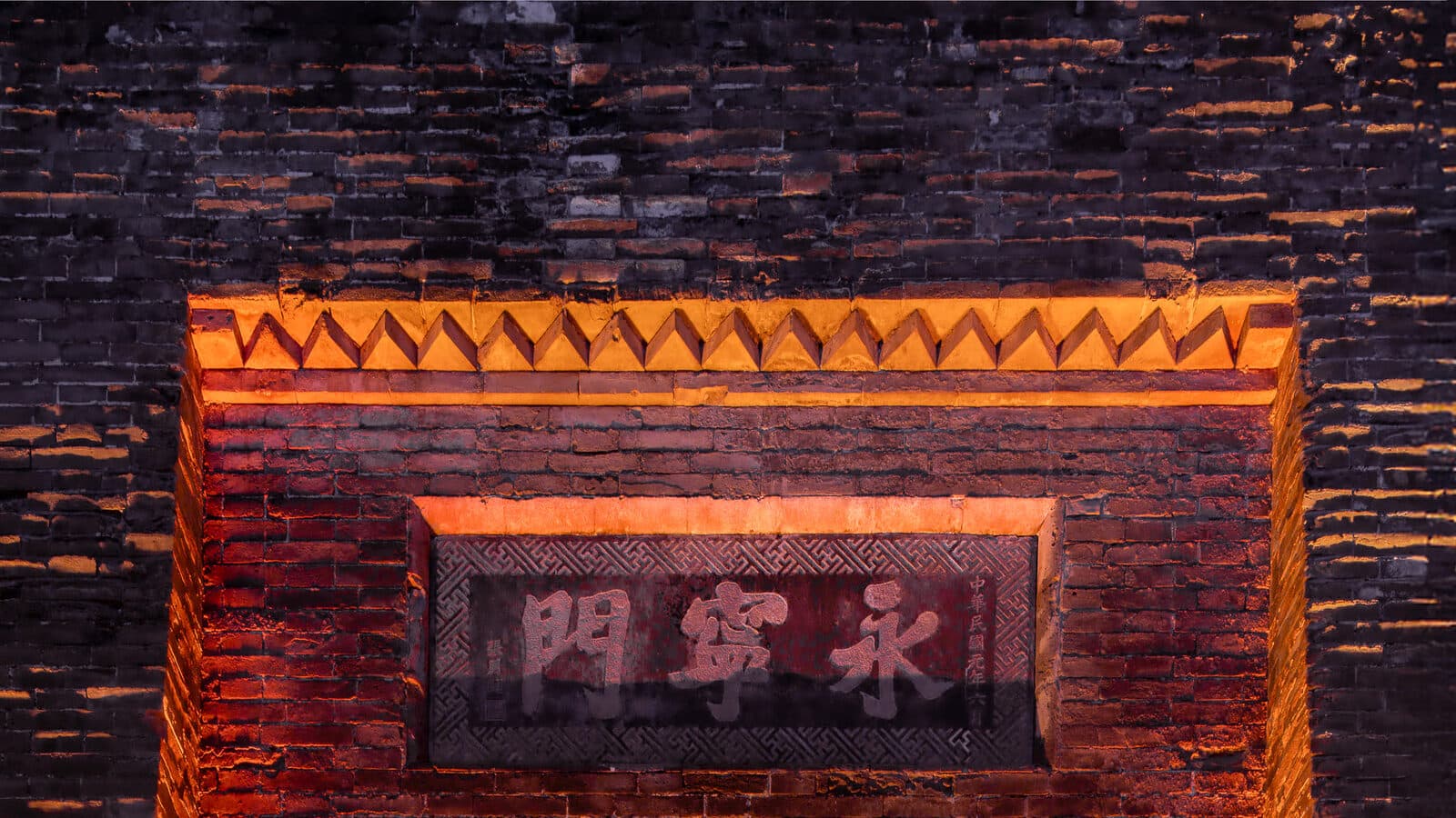 The brick face of Xi'an's city wall at night, with the gate's stone plaque