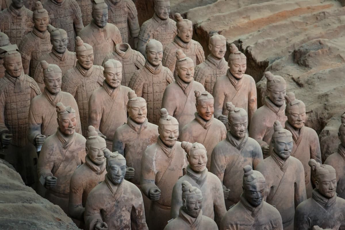 Rows of terracotta warriors in the pit, facial and topknot detail visible in the foreground